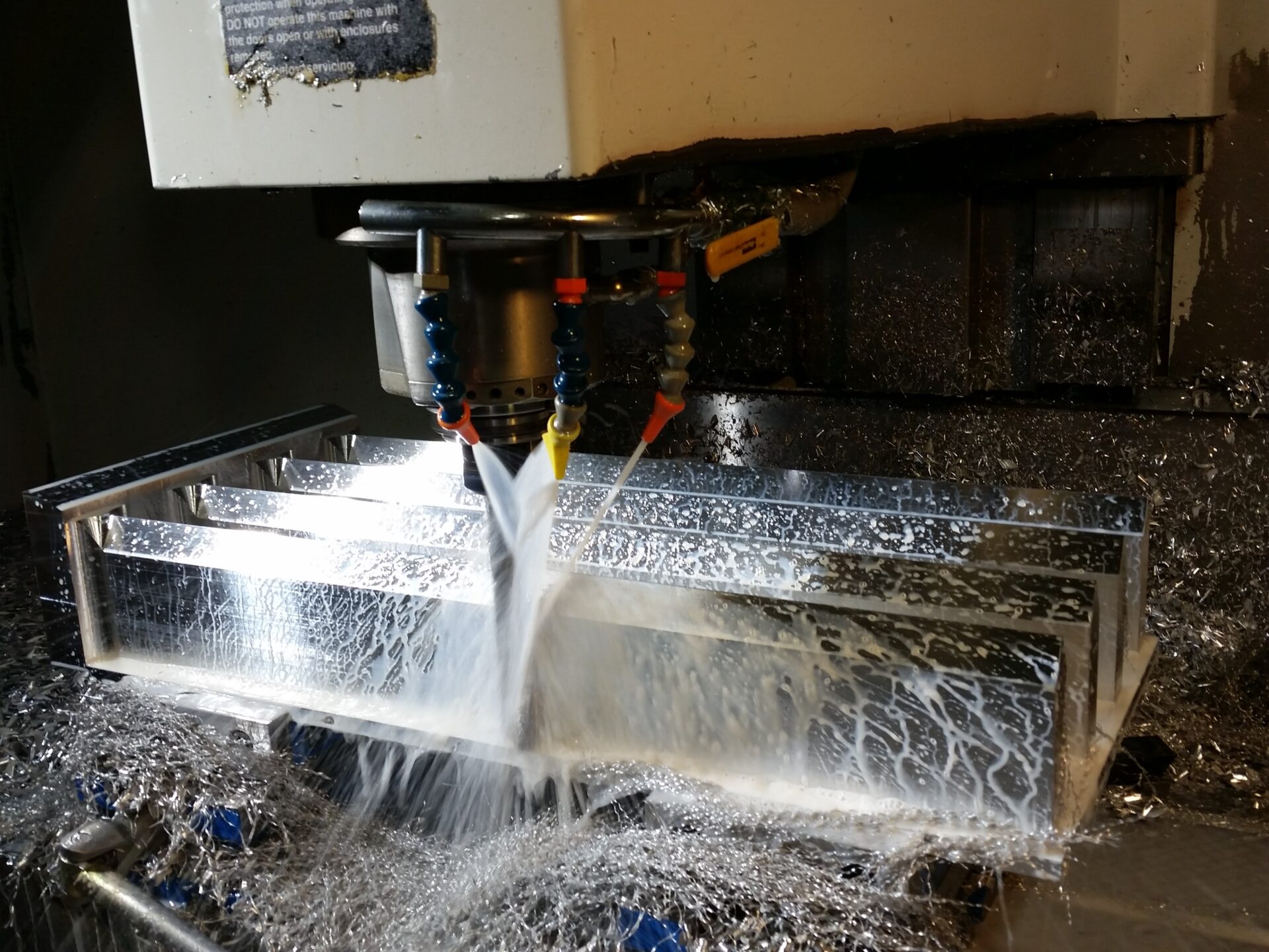 CNC spindle milling a metal block with coolant spray