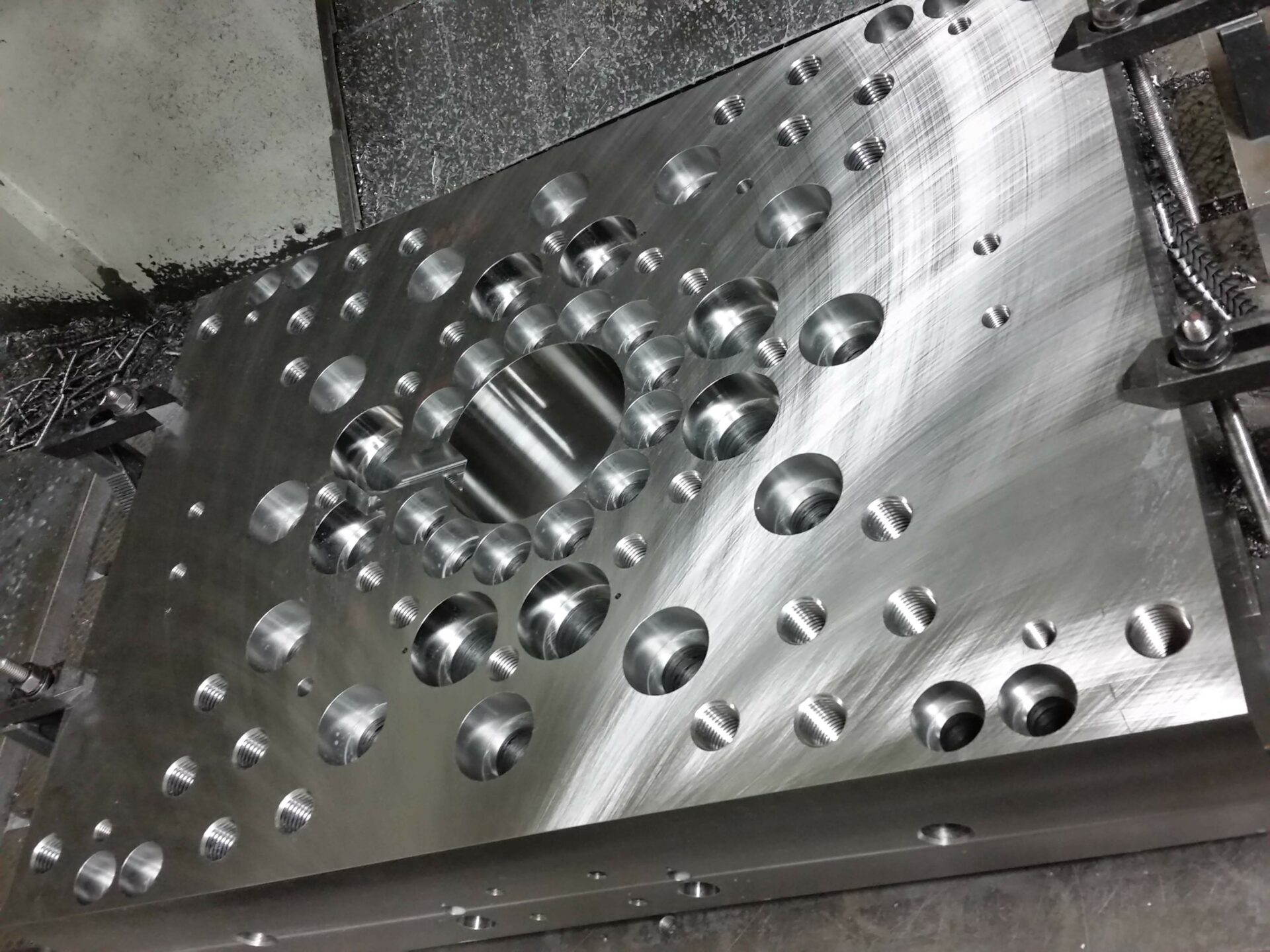 Thick machined metal plate with precision-drilled holes