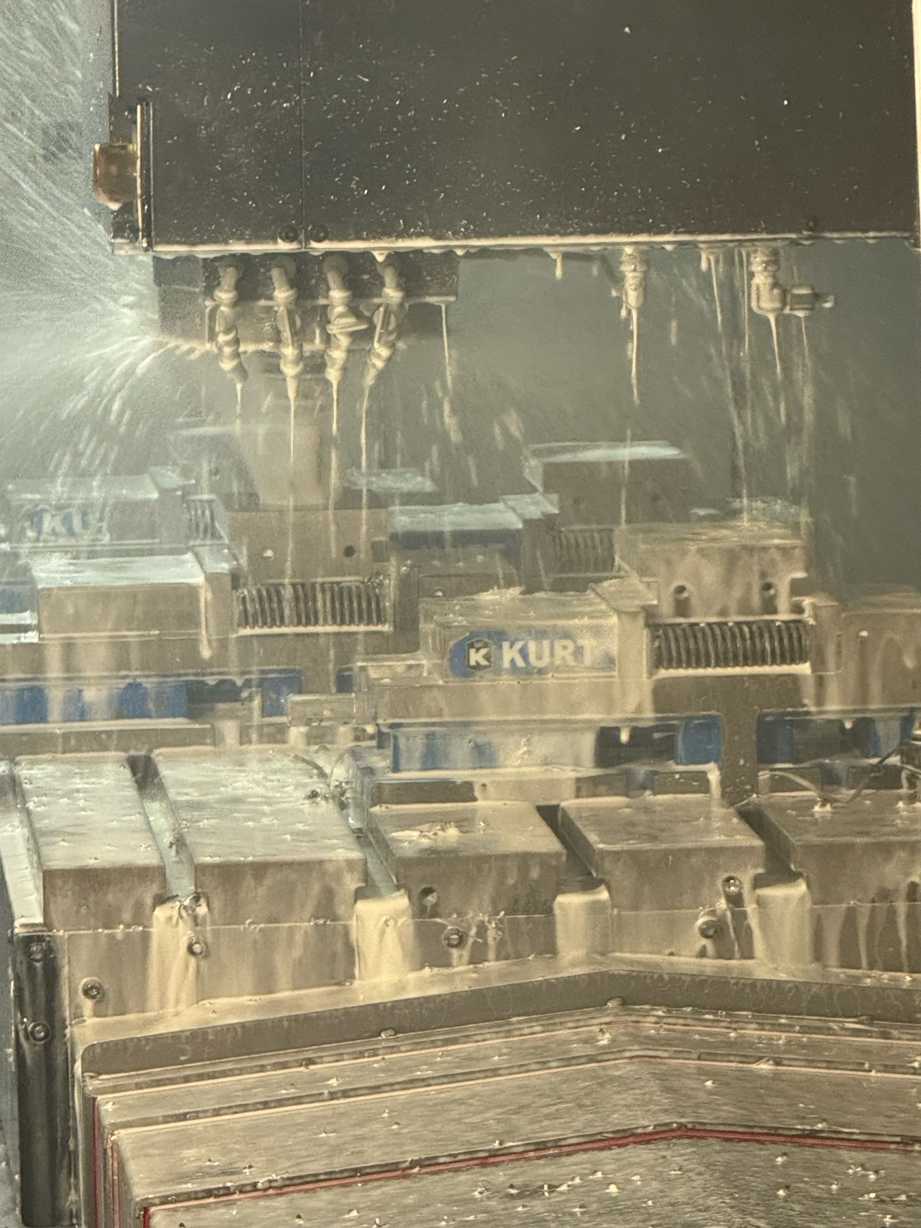 CNC milling in process — coolant spraying over Kurt vise workholding on the Nashville shop floor